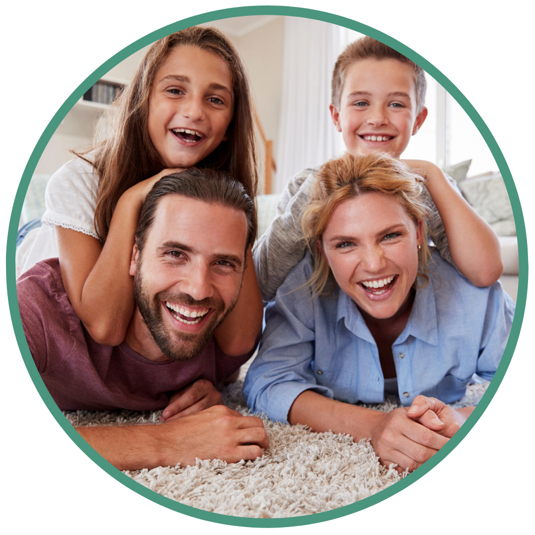 father, mother, and two children smile while laying on floor