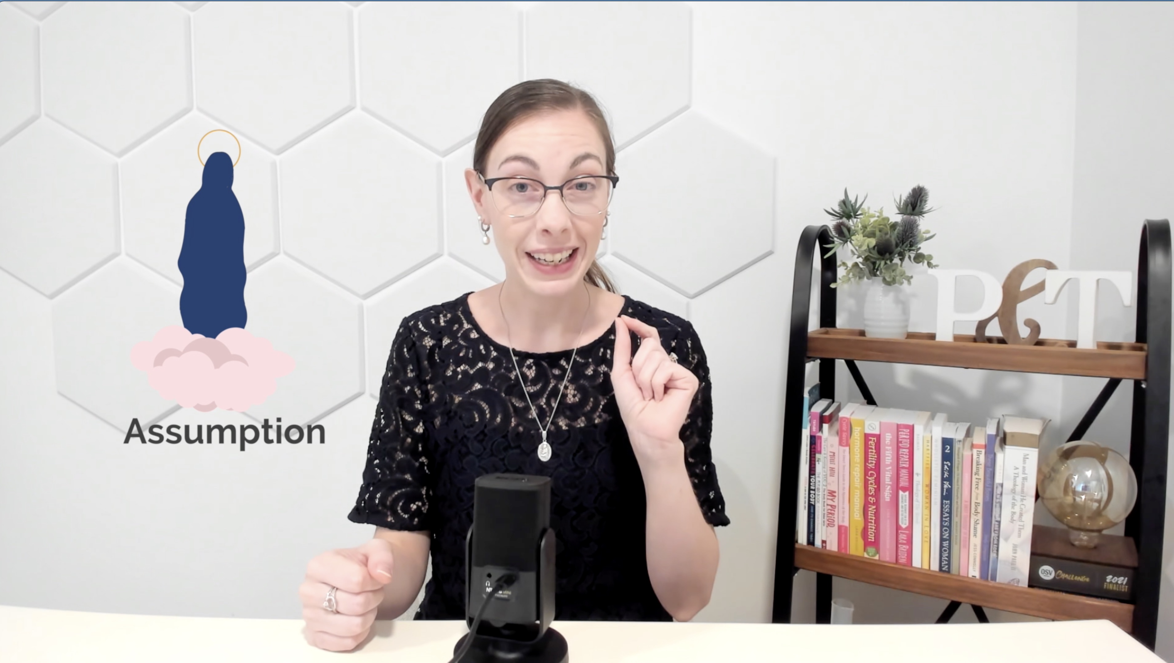video host in studio points at screen with image of mary's assumption into heaven